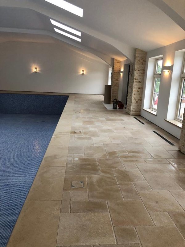 Stone floor running the length of an indoor pool room, with the pool to one side