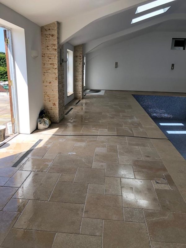 Indoor pool room with a stone floor, glazed doors and stone-clad pillars