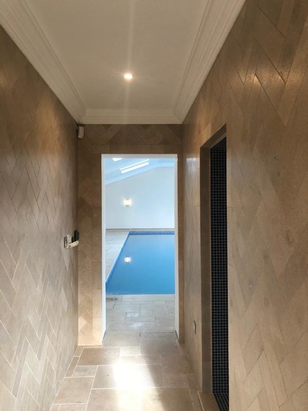 Herringbone-tiled corridor leading through to an indoor pool