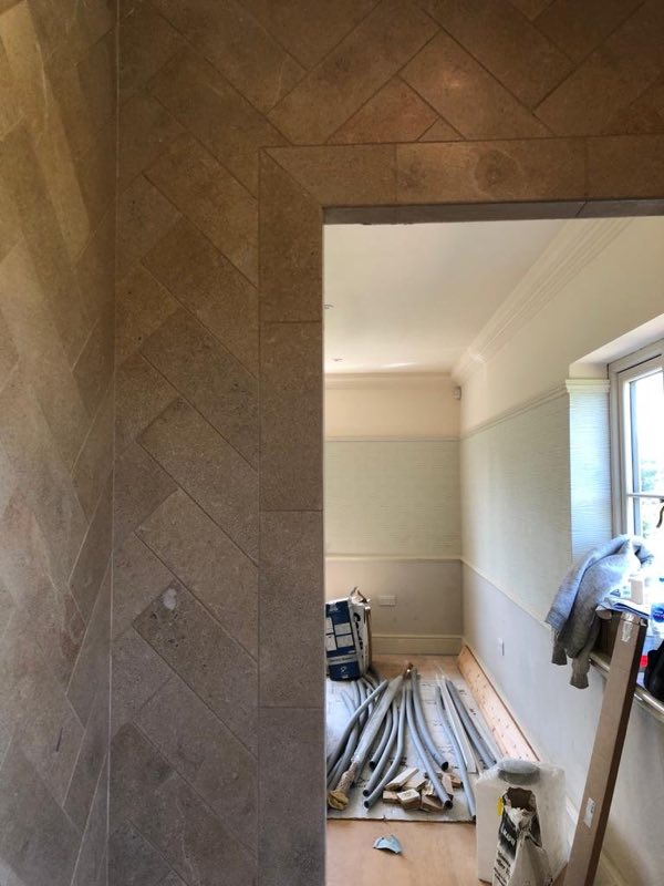 Herringbone-tiled doorway during fit-out, with the room beyond still being finished
