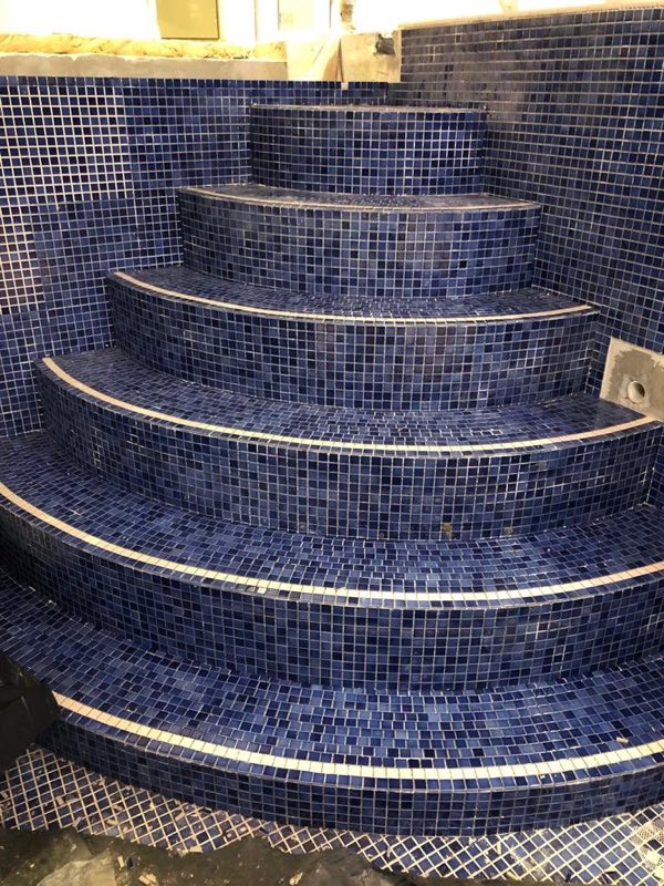 Curved pool steps tiled in dark blue mosaic