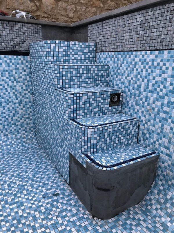 Pool steps under construction, tiled in blue and white mosaic