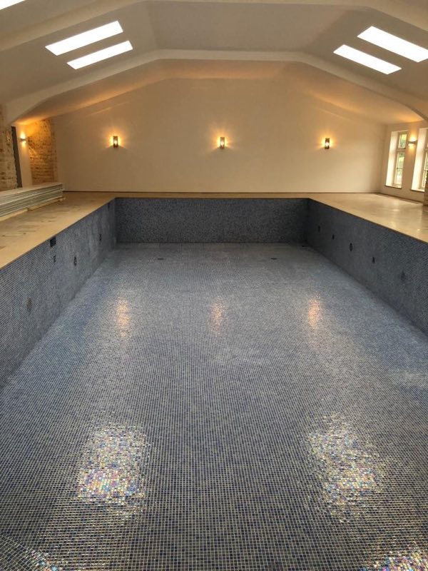 Empty mosaic-tiled indoor pool seen from one end