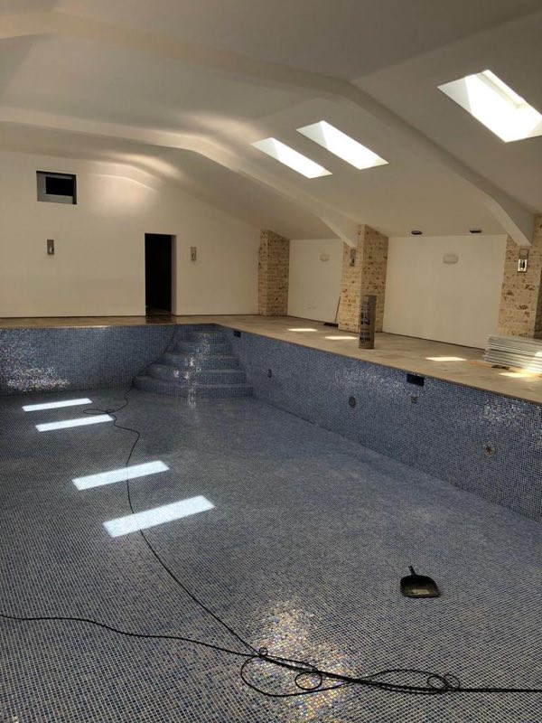 Indoor pool shell during tiling, with steps at the far end