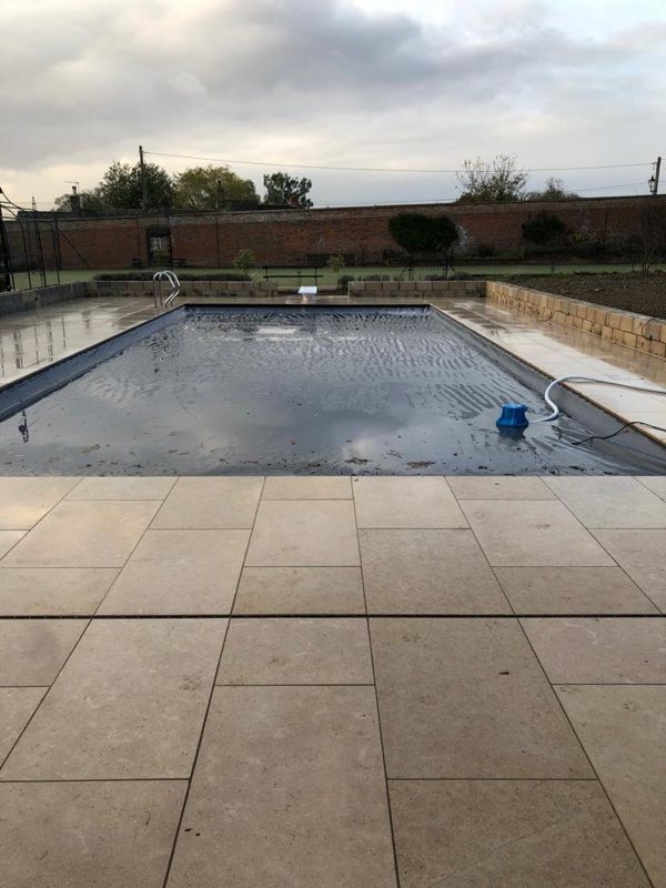 Outdoor pool with a pale stone terrace in a walled garden