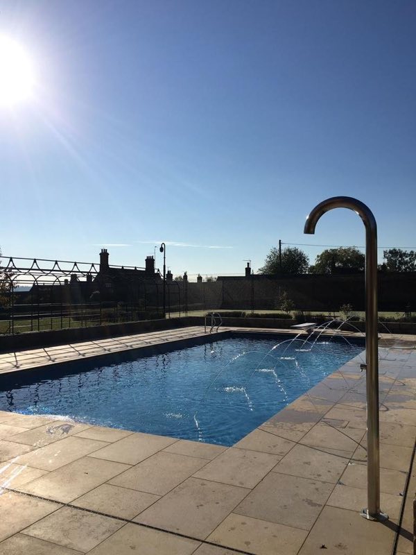 Outdoor pool with a stainless-steel shower on the terrace, in low sunshine