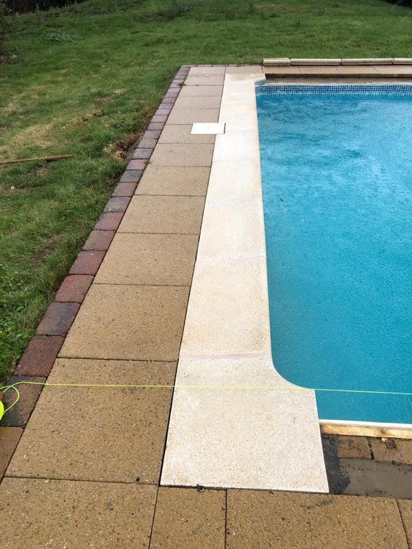 Pool coping and paving edge alongside a lawn