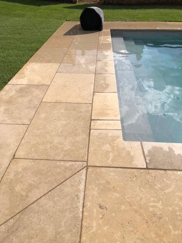 Stone terrace meeting the corner of an outdoor pool and the lawn