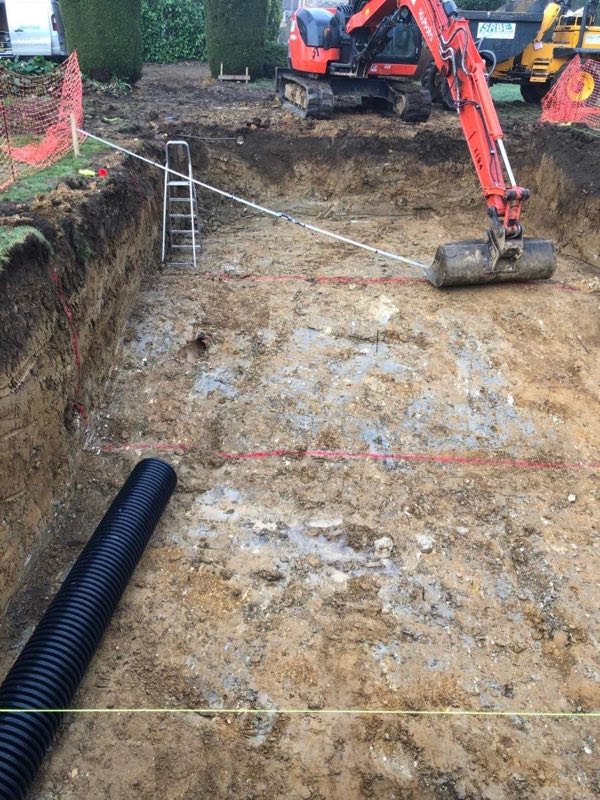 Excavation for a new outdoor pool, with a digger on site