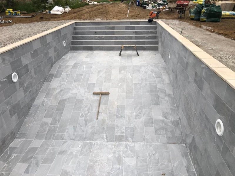 Grey-tiled pool shell with full-width steps, before filling