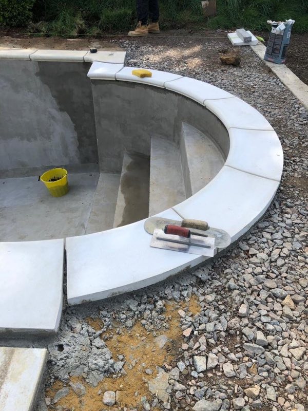 Curved steps being built with white coping stones