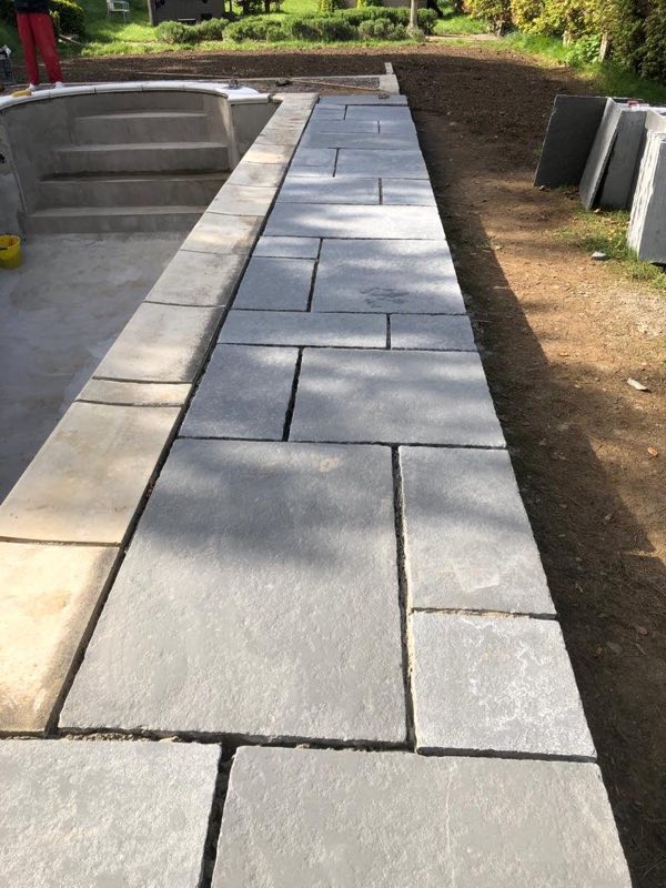 Grey stone paving laid alongside a pool under construction