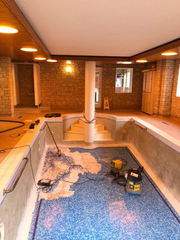 Mosaic being lifted from the floor of a drained indoor pool