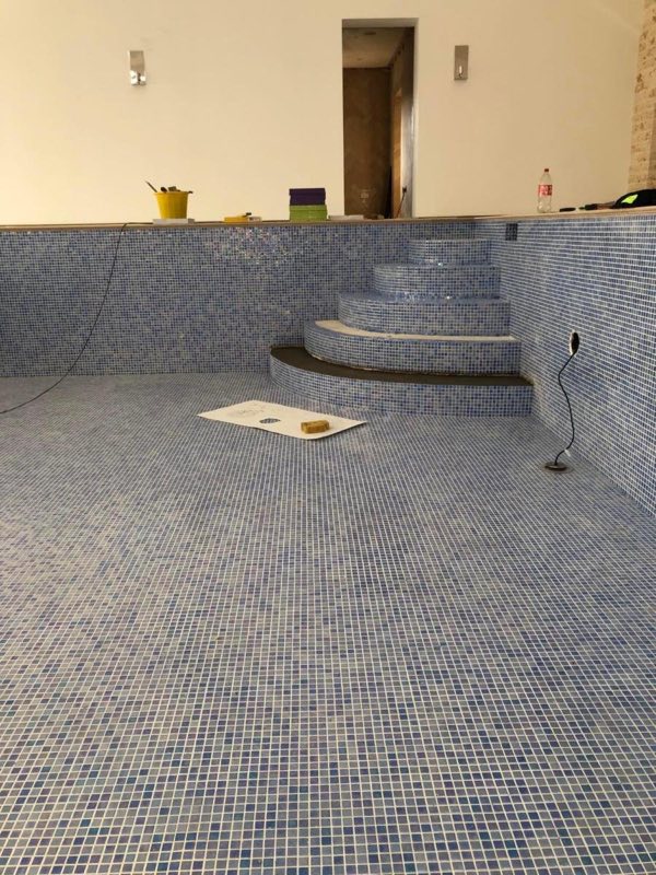 Pool tiled in blue mosaic, with the steps at the far end