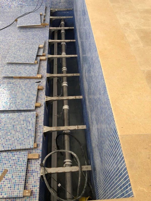 Mosaic tiling around a channel housing pool equipment